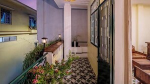 Un pasillo con piso a cuadros, una escalera con barandilla verde y una lámpara colgante.