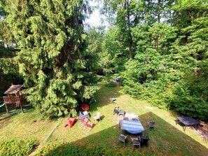 A garden with a wooden deck, a table with chairs, and a large tree. - The 3 Pignons Gourmet Retreat (Noisy-sur-École)