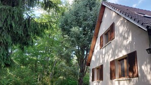 A house with a sloped roof, wooden shutters, and a garden with chairs and a table. - The 3 Pignons gourmet refuge (Noisy-sur-École)