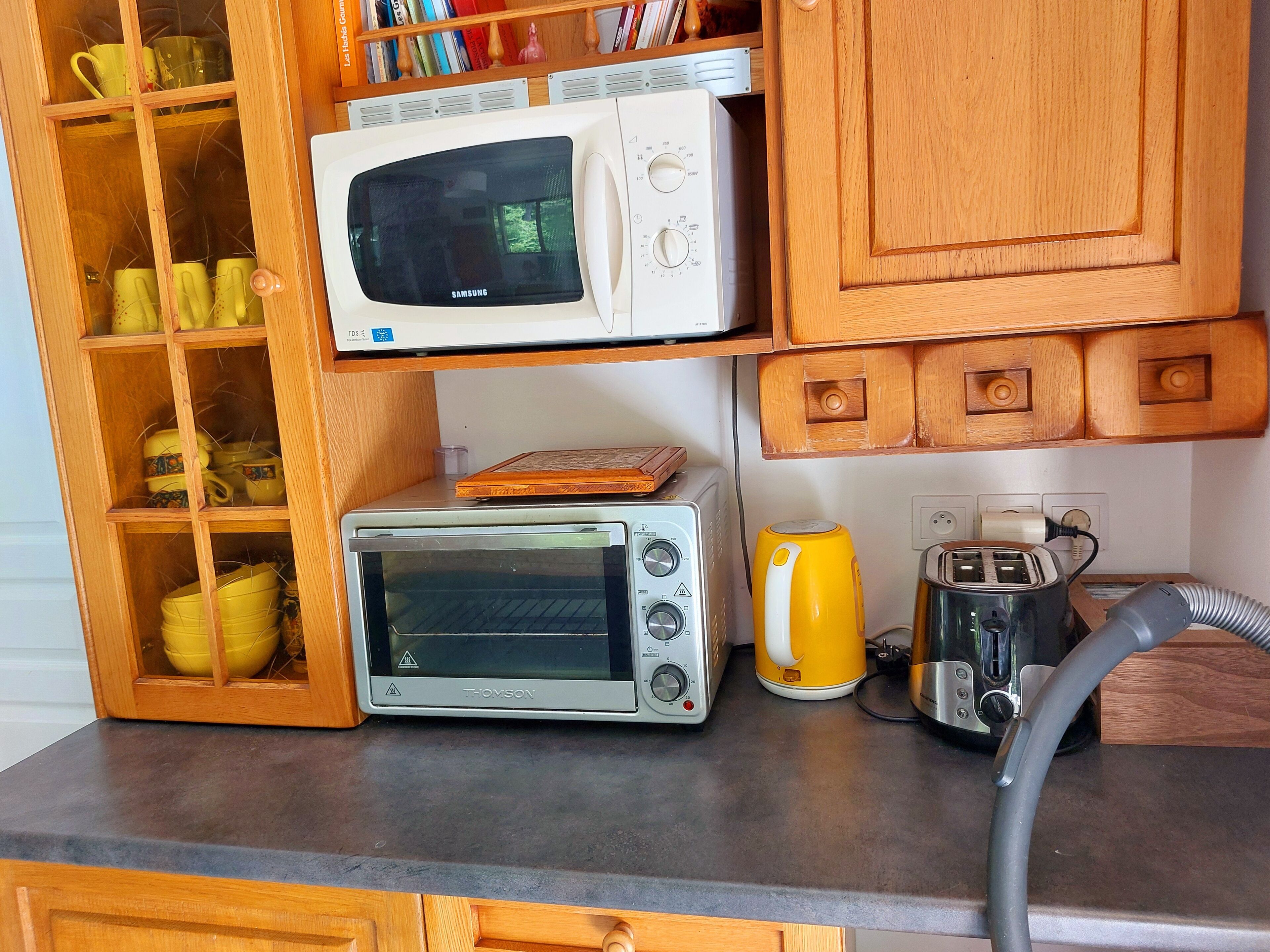A kitchen with a microwave, toaster oven, and kettle on the countertop.