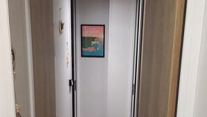 Un pasillo con piso de madera, paredes blancas y un cuadro enmarcado en la pared.
