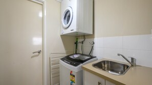 Eine kompakte Küche mit einer eingebauten Waschmaschine, einem Spülbecken und einem Schrank darüber.