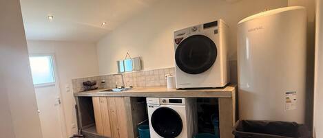 A laundry room with a washing machine, dryer, and stacked laundry baskets.