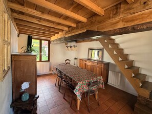A rustic dining area with a wooden table, chairs, and a staircase. - Le Refuge, 140m² longère located near Montreuil sur mer. (Beaumerie-Saint-Martin)
