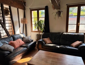 A cozy living room with two leather sofas, a wooden coffee table, and a potted plant. - Le Refuge, 140m² longère located near Montreuil sur mer. (Beaumerie-Saint-Martin)