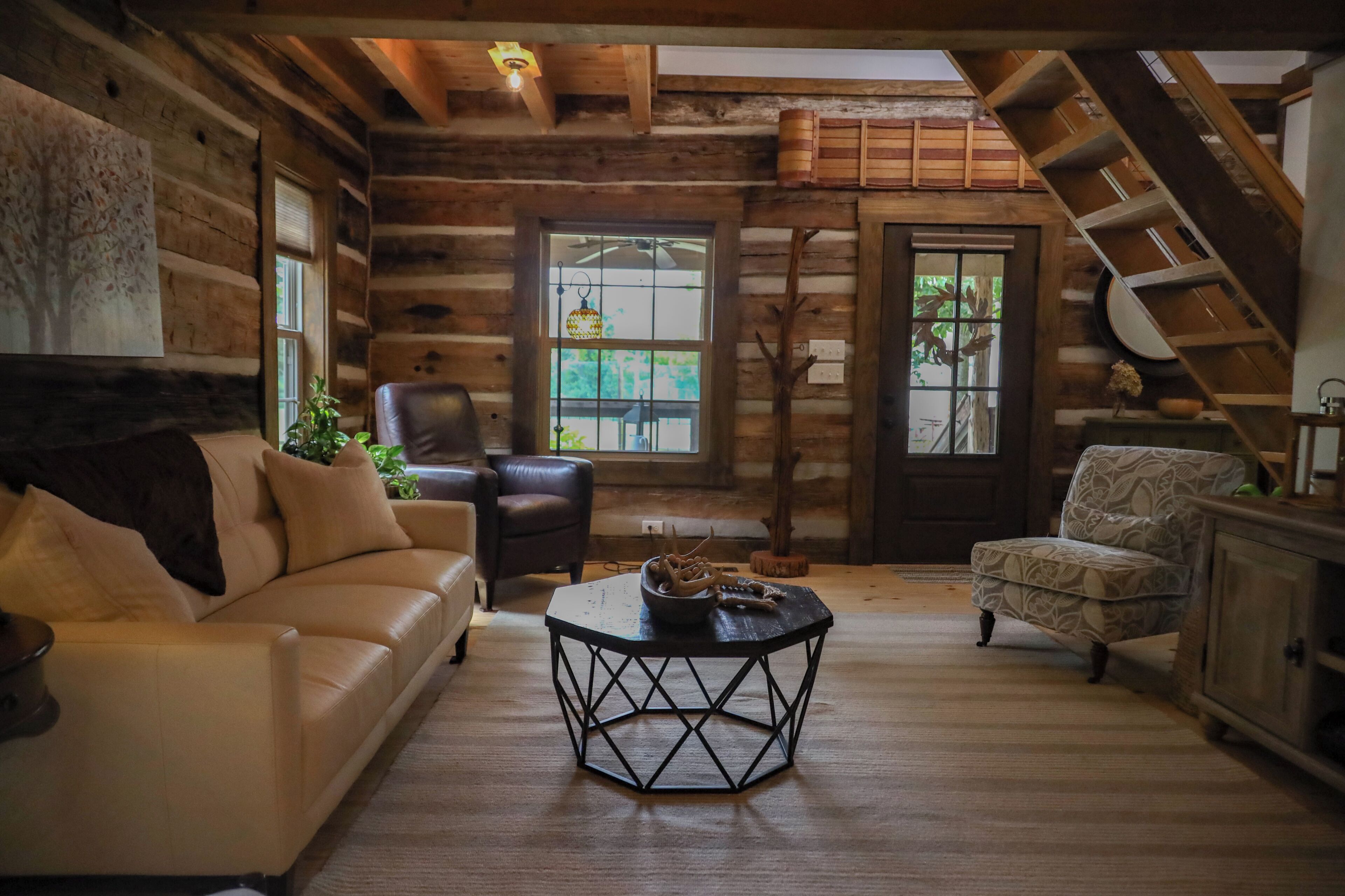 A log cabin interior with a sofa, armchair, and a coffee table.