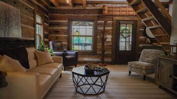 A log cabin interior with a sofa, armchair, and a coffee table.
