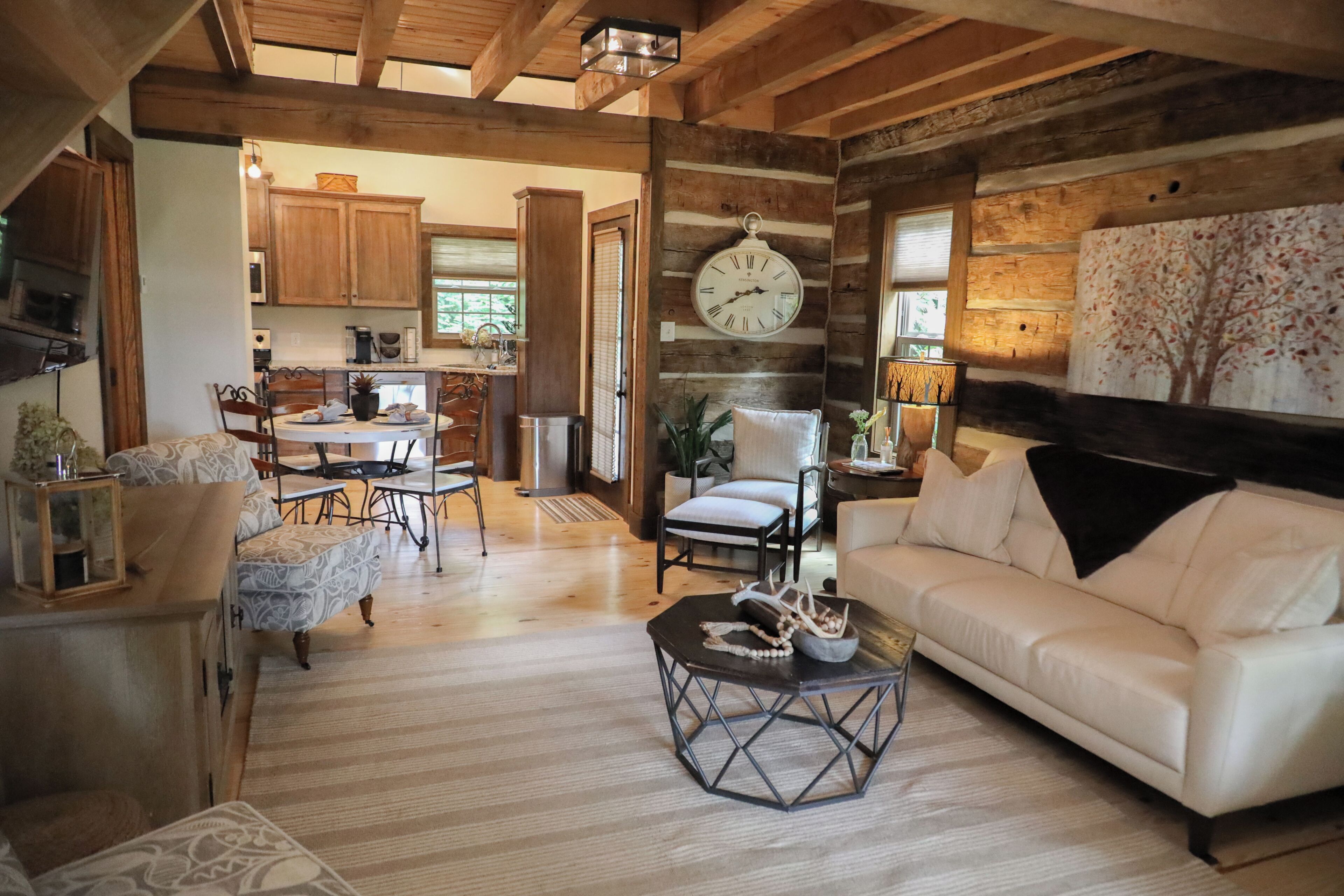 A rustic interior with a dining area, a white sofa, and a clock on the wall.