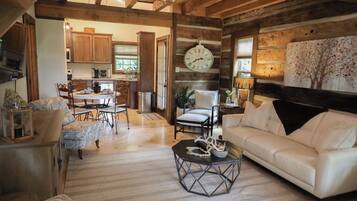 A rustic interior with a dining area, a white sofa, and a clock on the wall.