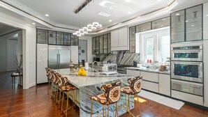 Een moderne keuken met een marmeren eiland, roestvrijstalen apparatuur en een bijzondere kroonluchter.