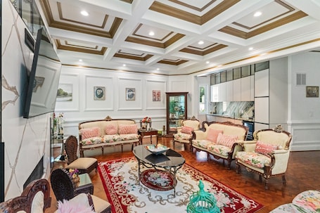 A spacious living room with ornate ceiling, plush sofas, a coffee table, and a television.. McLean Estate | 7BD | BBQ-Parking-Luxury Theater