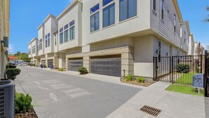 Un edificio moderno con diversi appartamenti, un marciapiede pulito e un prato ben curato.