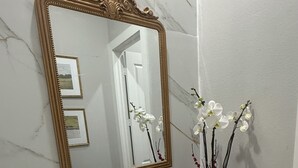 Un bagno con un lavabo in marmo, un rubinetto dorato e un grande specchio decorativo.
