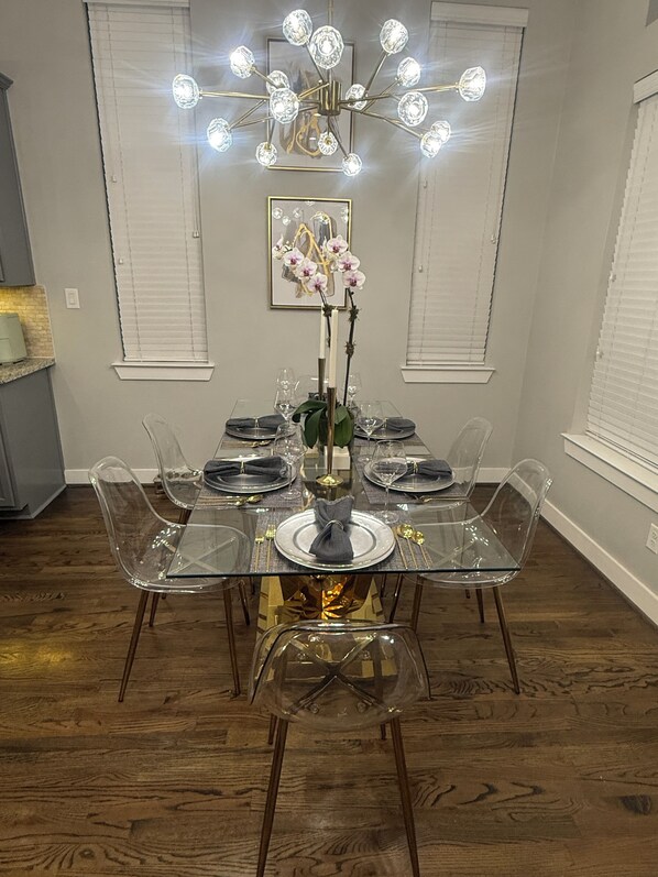 A dining area with a glass table, clear chairs, a chandelier, and a framed picture on the wall. - 5 minute walk to FIFA Fan Festival. (Houston)