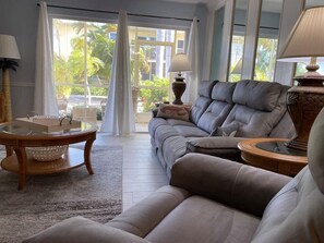 A living room with a sofa, two side tables, a coffee table, and a window with curtains. - Beautiful 2-bedroom, 2-bath condo perfect escape to relax and fish in Marathon (Marathon)
