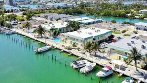 Un puerto deportivo con barcos amarrados, un edificio de techo plano y una vista despejada del océano.