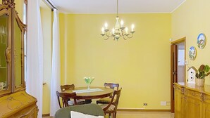 A dining area with a chandelier, a round table, chairs, a sofa with a pillow, a wooden cabinet, and a mirror. - Una Finestra sul Lago by Interhome (Bellano)