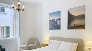 A hotel room with a bed, two bedside lamps, a chair, a small table, and two wall-mounted pictures. - Una Finestra sul Lago by Interhome (Bellano)