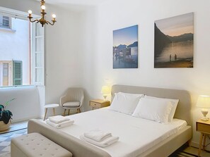 A hotel room with a bed, two bedside lamps, a chair, a small table, and two wall-mounted pictures. - Una Finestra sul Lago by Interhome (Bellano)