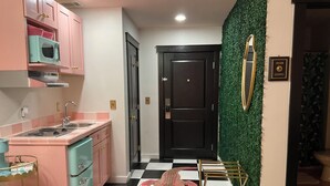 A kitchen with pink cabinets, a black and white checkered floor, a crocodile rug, and a gold ladder. - Labor Day Opening🌴Last minute PCB Getaway  The Pink Panama at Origin at Seahaven (Panama City Beach)