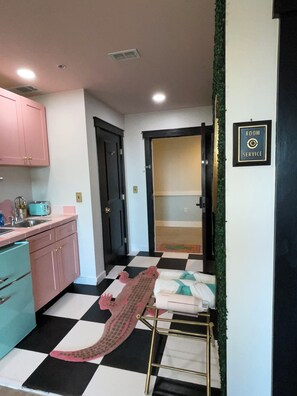 Una habitación con piso a cuadros, un lavamanos, armarios y una puerta que da a otra estancia.