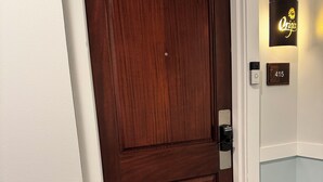 A wooden door with a doorknob, a wall-mounted light, and a doorbell. - Labor Day Opening🌴Last minute PCB Getaway  The Pink Panama at Origin at Seahaven (Panama City Beach)