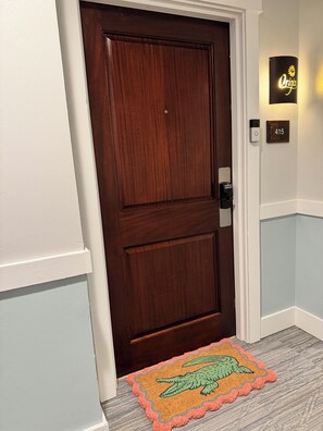 A wooden door with a doorknob, a wall-mounted light, and a doorbell.