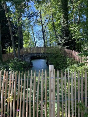 A stone bridge over a calm water body, surrounded by lush greenery and a wooden fence. - La Villa Coqueret - LUSIGNY SUR BARSE (LUSIGNY SUR BARSE)