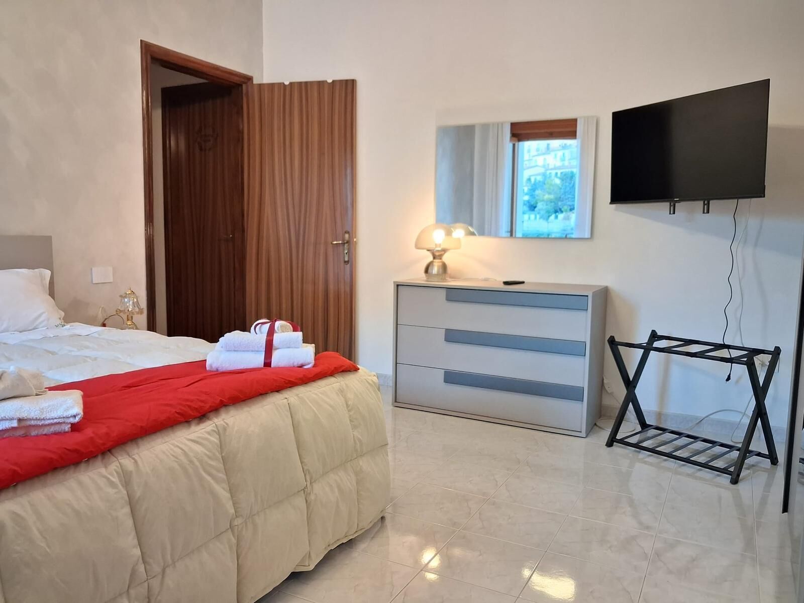 Une chambre d’hôtel avec un lit, une commode, une télévision et une fenêtre.