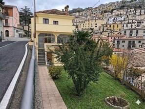 A residential area with a yellow building, a narrow road, and a hillside of closely packed houses.