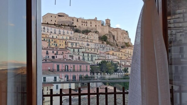 Un balcón con vista a edificios coloridos y una construcción de aspecto fortificado.