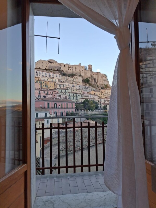 A balcony with a view of colorful buildings and a fortress-like structure.