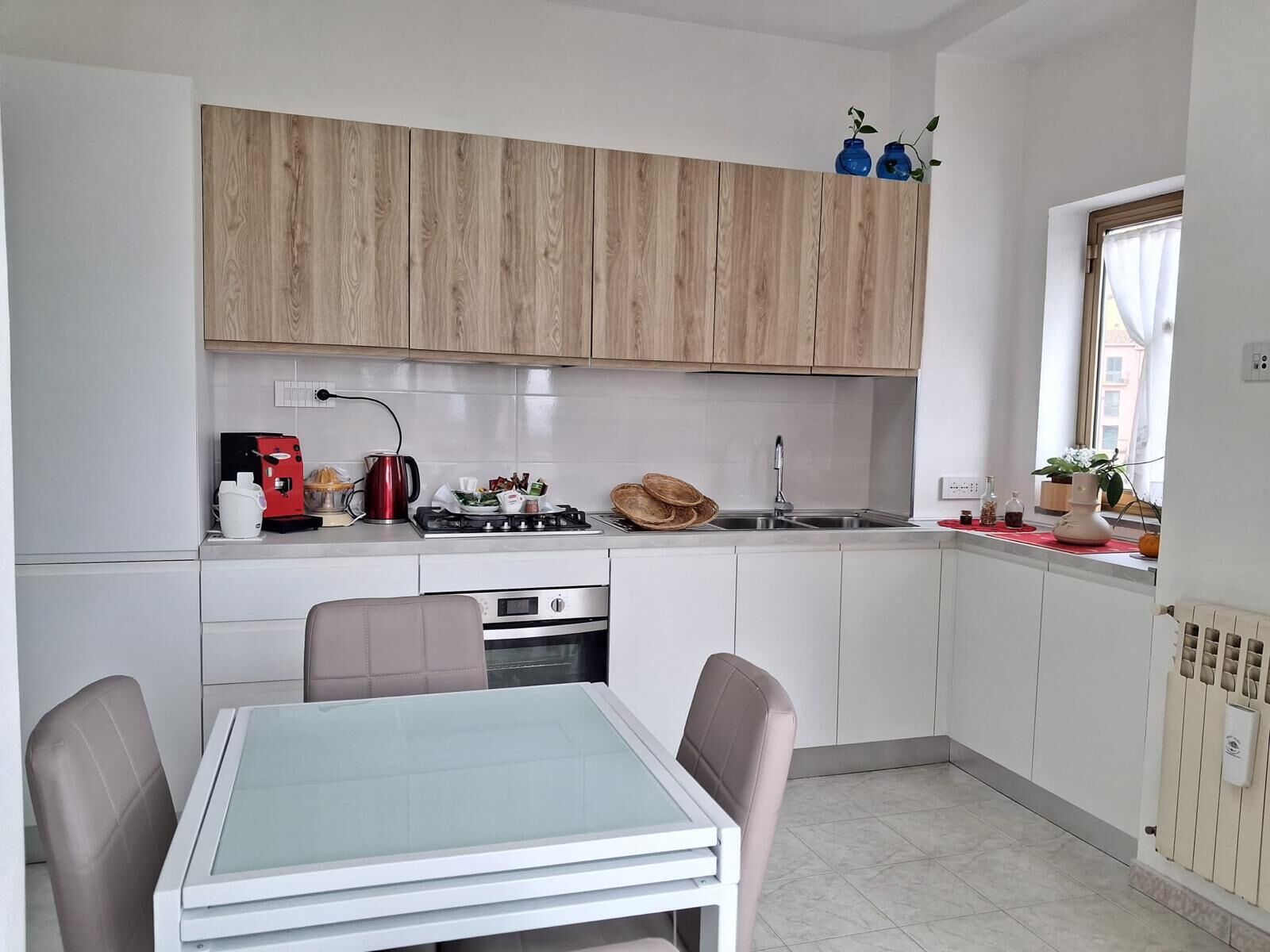 Una cucina compatta con un tavolo da pranzo, sedie, un fornello e un lavandino.