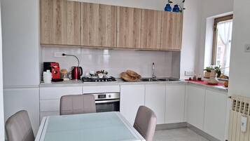 Una cucina compatta con un tavolo da pranzo, sedie, un fornello e un lavandino.
