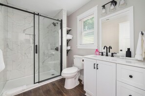 A bathroom with a glass shower enclosure, white toilet, and vanity with a mirror.