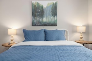 Une chambre à coucher avec un lit, deux lampes de chevet, un tableau et une table ronde.