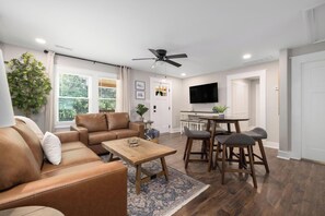 A living room with a sofa, coffee table, and dining area with chairs.