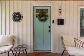 A teal door with a wreath, a 'Bird's Nest' sign, and the number 107 on the wall.