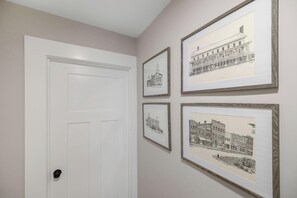 A hallway with a white door and four framed black-and-white architectural drawings on the wall.