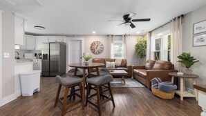 A modern living room with a dining area, a kitchen, and a ceiling fan. - Walk to Downtown Jboro · Remodeled 3BR · Sleeps 6 (Jonesborough)