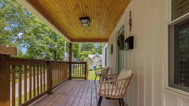 A wooden deck with a railing, two wicker chairs, a hanging light fixture, and a house number 107. - Walk to Downtown Jboro · Remodeled 3BR · Sleeps 6 (Jonesborough)