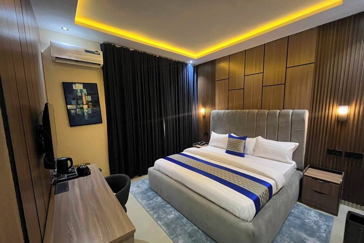 Habitació d'hotel moderna amb un llit gran, un escriptori i una televisió.