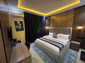 Habitació d'hotel moderna amb un llit gran, un escriptori i una televisió.