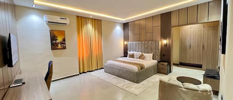 A modern bedroom with a large bed, bedside tables, a TV, and a wardrobe.