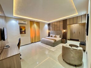 Un dormitorio moderno con una cama grande, mesitas de noche, un televisor y un armario.