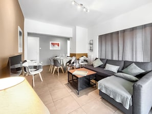 A modern living room with a sofa, a dining table set for four, and a TV. - T4 modern, bright and central with balcony Apartment in residence Toulon (Toulon)