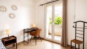 Quarto com escrivaninha, cadeira, luminária e vista através de uma porta deslizante.