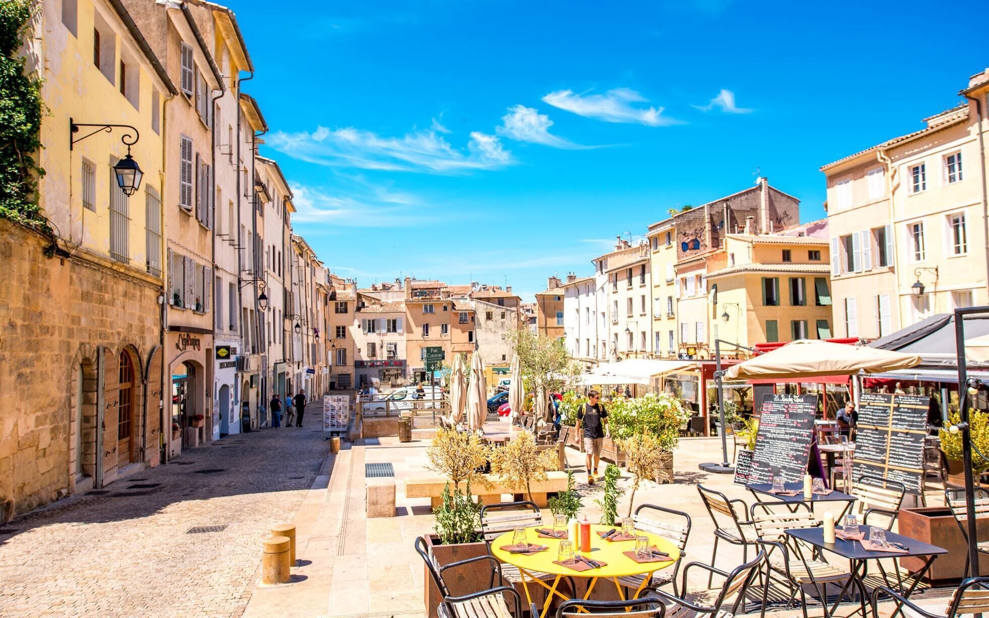 Une rue pavée bordée de bâtiments historiques, des terrasses de café où l’on peut s’asseoir et un ciel d’un bleu éclatant.