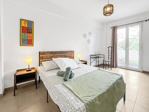 A bedroom with a bed, two bedside tables, a lamp, a chair, a small table, and a view of the outside through a sliding door. - T4 modern, bright and central with balcony Apartment in residence Toulon (Toulon)