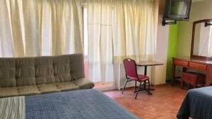 Una habitación con cama, una silla, televisión y escritorio.